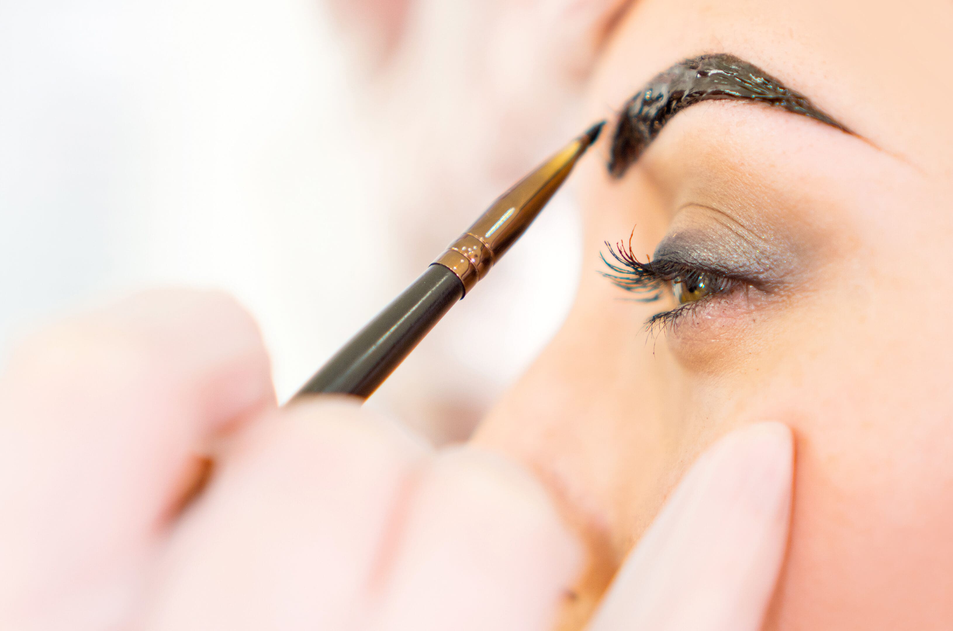 A woman is putting makeup on her eyes.