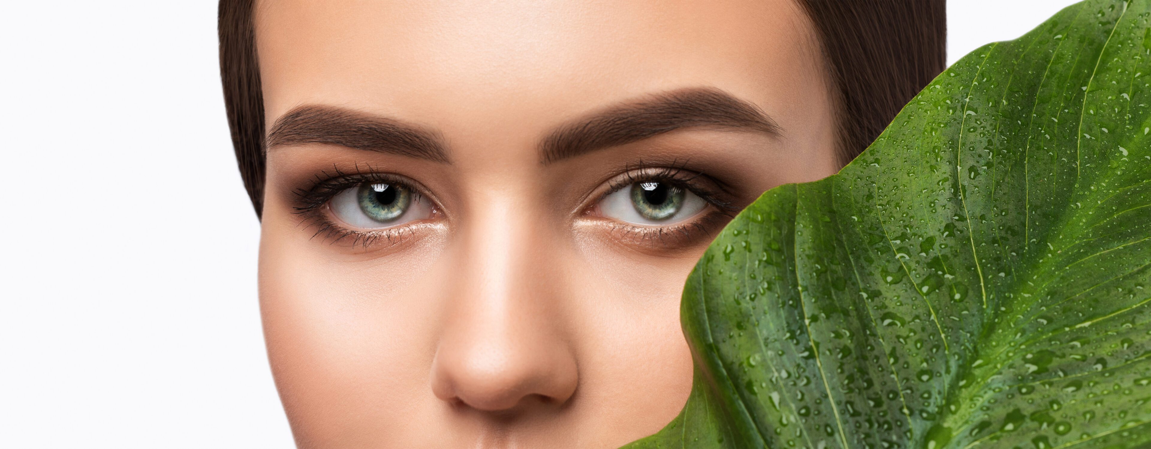 A woman with green eyes holding a leaf.